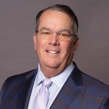 Smiling man in suit with glasses.
