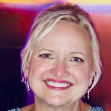 Smiling woman with blonde hair and earrings.