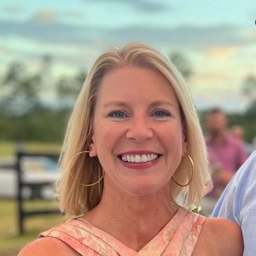Smiling woman with blonde hair and hoop earrings.