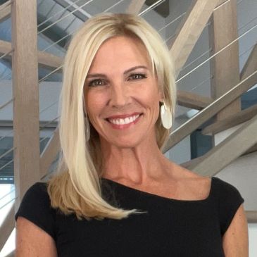 Smiling woman with blonde hair and black dress.