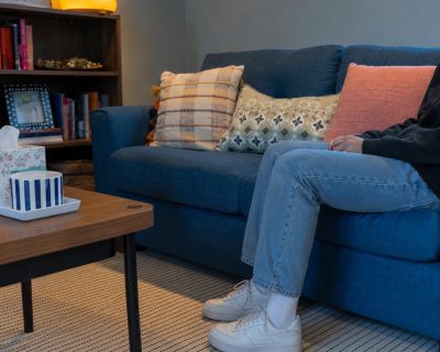 Person sitting on a blue couch with decorative pillows.