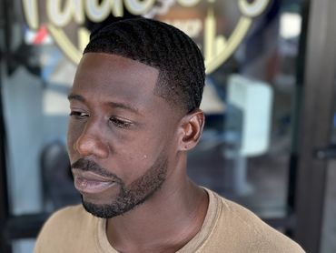 Man with fresh fade haircut standing outside Fade City barbershop.