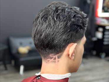 Man with a fresh haircut featuring a stylish design shaved on the back of his neck.