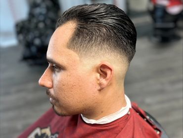 Man with a sleek, slicked-back haircut and a clean fade on the sides.