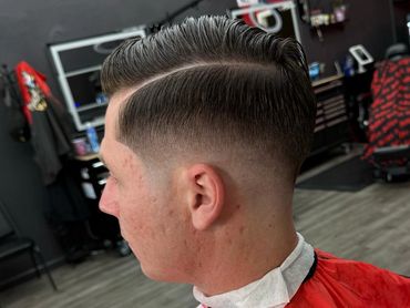 Fresh fade haircut with a clean side part in a modern barbershop.