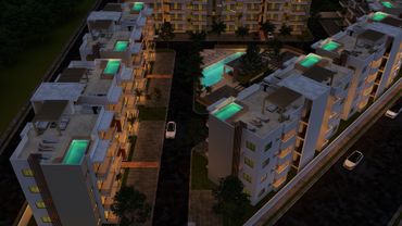 Night view of illuminated apartment buildings with rooftop pools and a central swimming pool.