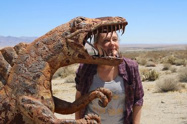 woman apparently in the sharp teeth of a dinosaur sculpture in the Ansa-Borrego Desert State Park, C