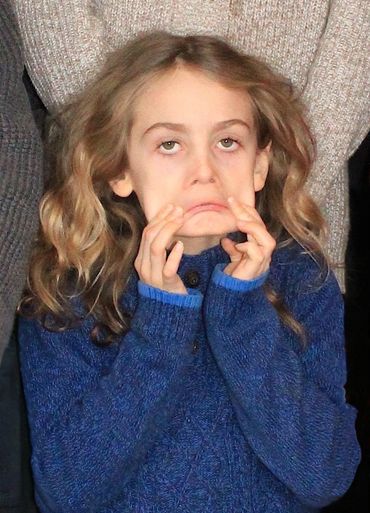 Candid of a young girl is making a face by pulling down her eyes while looking, and the corners of