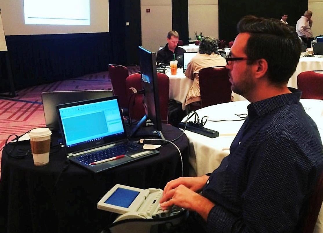 Thomas captioning with this steno machine at a busy conference.
