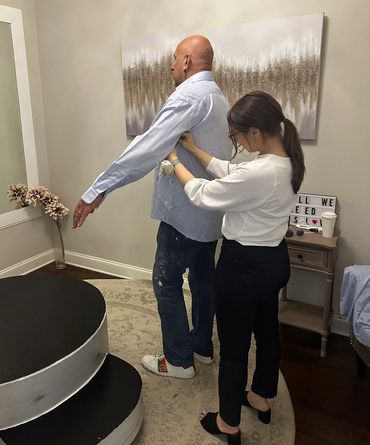 Woman helping man put on a dress shirt indoors.