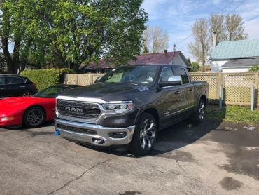 A gray RAM pickup truck parked beside a red sports car.