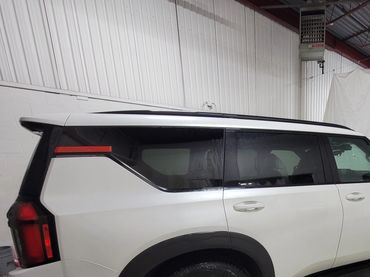 White SUV parked indoors near a white tarp.