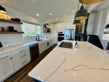 Modern kitchen with marble countertops and stainless steel appliances.