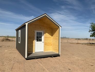 Small wooden shed with a white door outdoors.