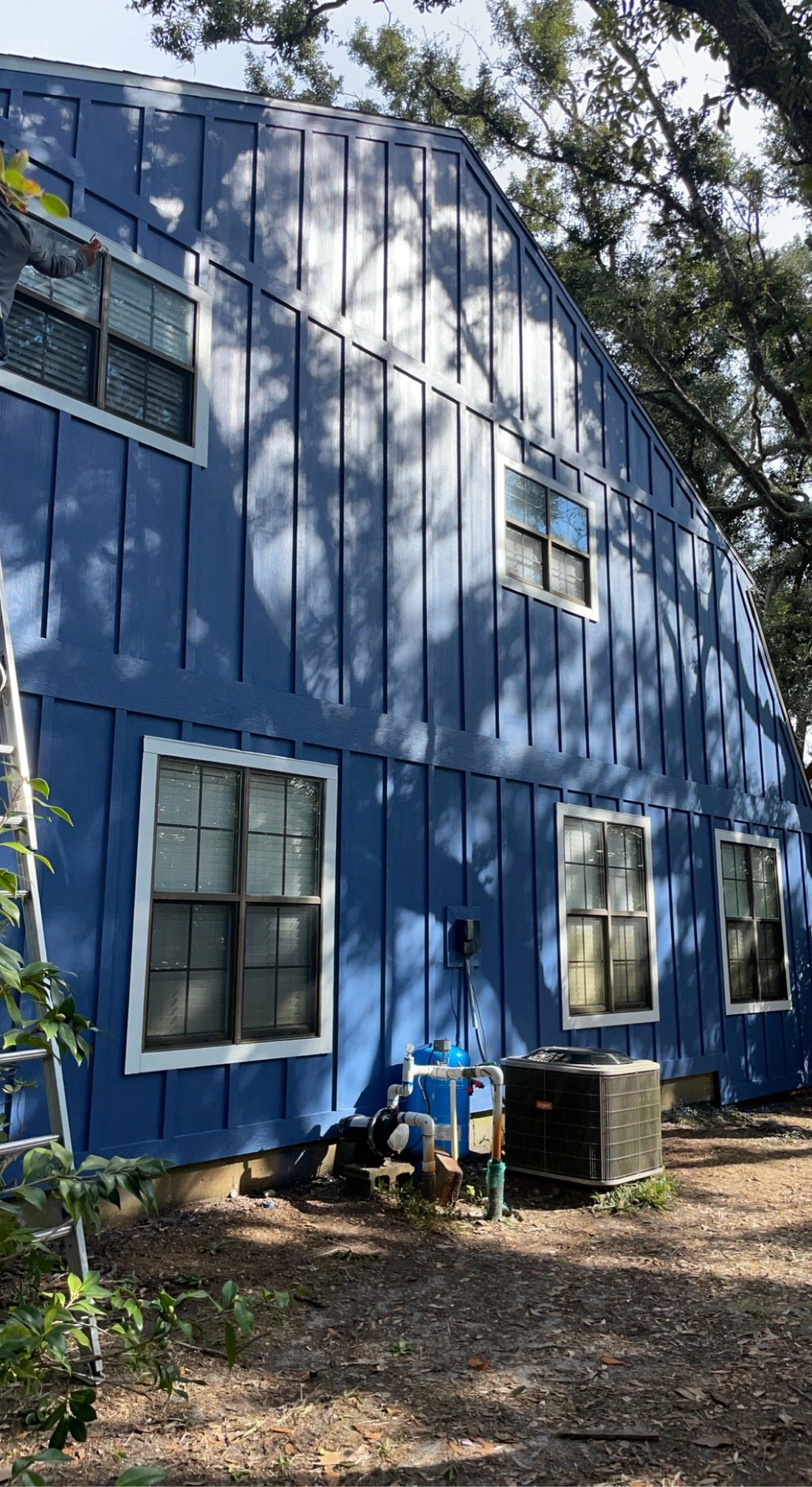 Blue house exterior with white-trimmed windows and outdoor equipment.