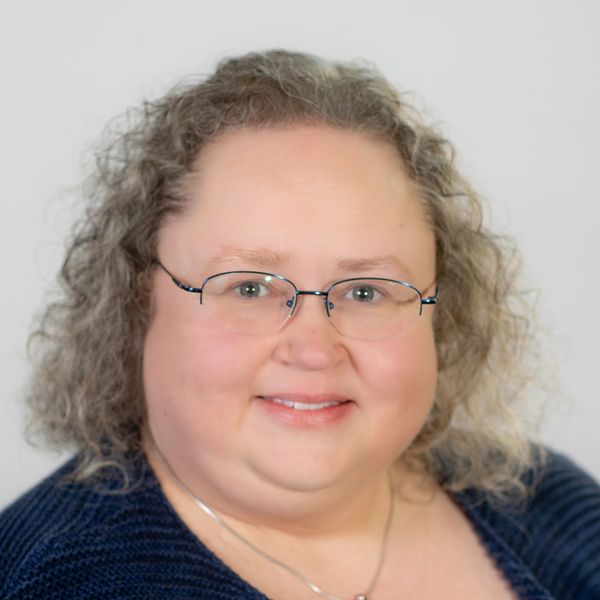 Smiling woman with glasses and curly hair.