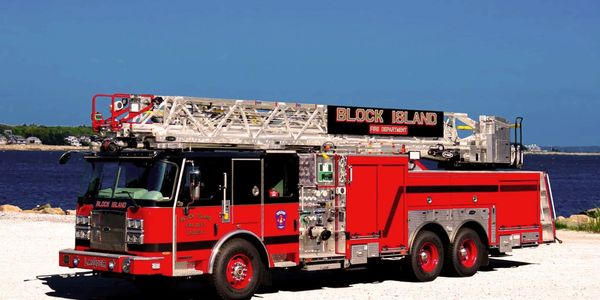 An aerial ladder truck is parked by the harbor.