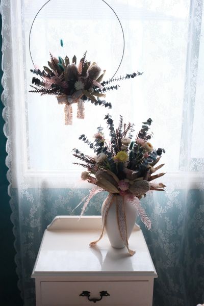 Dried flower arrangements by a lace-curtained window.