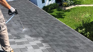 Person spraying liquid on a roof with a hose.