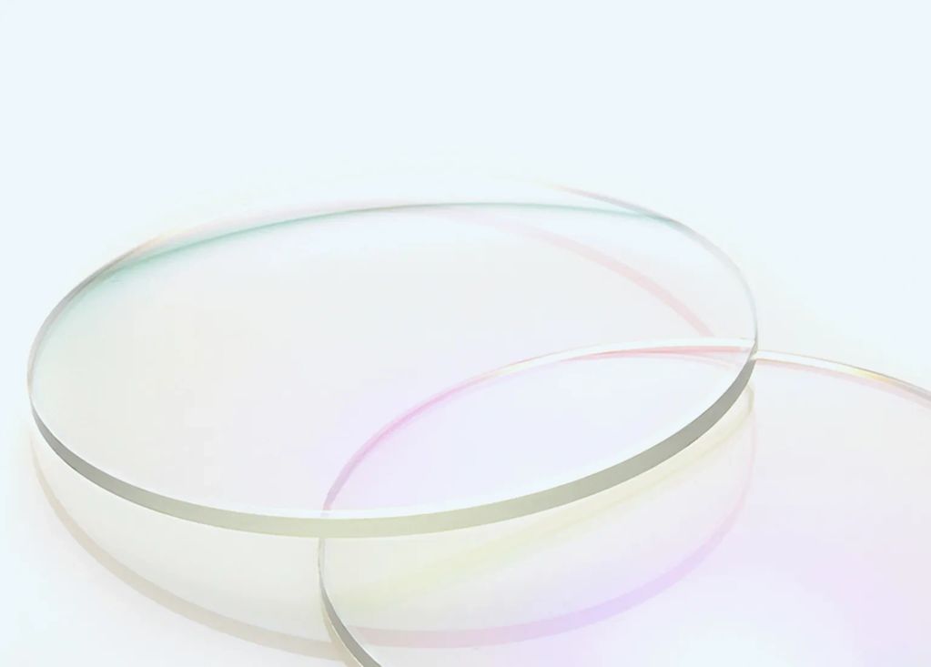 Two clear, round glass lenses overlapping on a white surface.