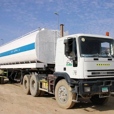 White Iveco tanker truck parked on a dirt road under a blue sky.
