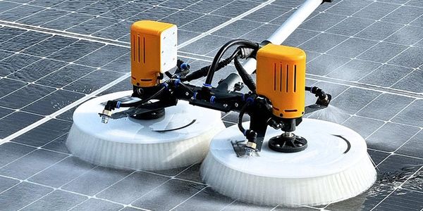 Automated brush device cleaning solar panels on a roof.