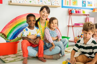 Preschool teacher with children playing at kindergarten.