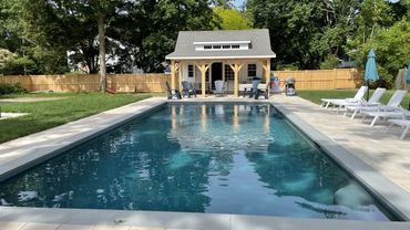 A serene backyard pool with lounge chairs and a wooden pool house.