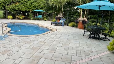 Backyard pool area with blue umbrellas and lounge chairs.