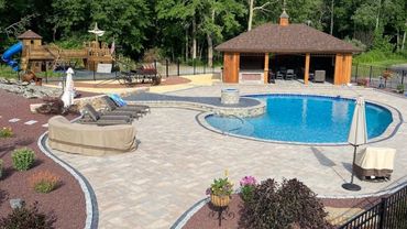 Spacious backyard pool area with patio furniture and a wooden pavilion.