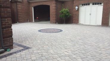 Brick driveway with circular patterned center in front of a garage.