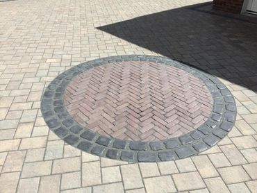 Circular patterned brick design on a paved surface with shadow.