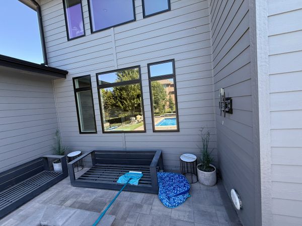Outdoor seating area with windows reflecting a pool and greenery.