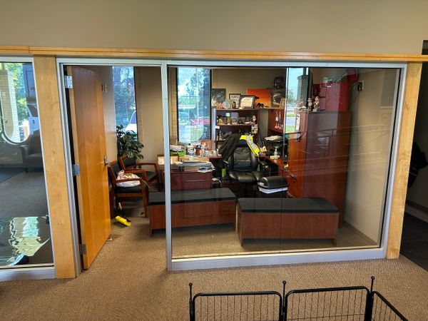 A neat office with wooden furniture and glass walls.