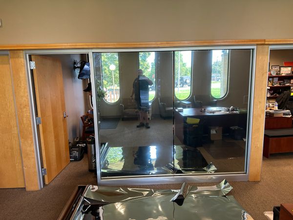 Reflection of a person in a large, glossy mirror in an office setting.