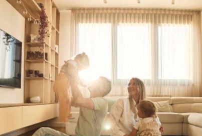 A happy family enjoys time together in a sunlit living room.