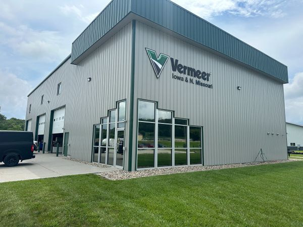 Modern Vermeer building with large glass windows and green lawn.