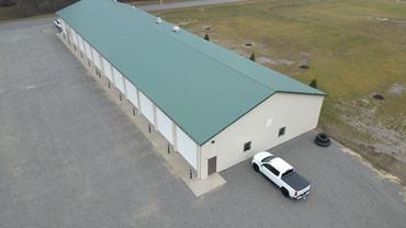 A long, beige storage building with a green roof
