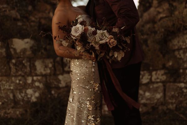 A bride wearing a gold sequinned wedding dress and a groom at Jervaulx Abbey in Yorkshire.