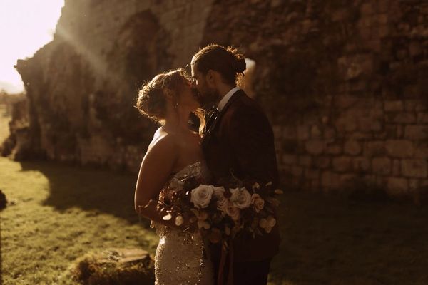 A bride and groom kiss in the middle of Jervaulx Abbey in Yorkshire.