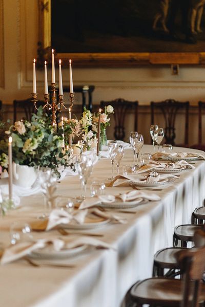 A table is set for a wedding breakfast with white linens, candles and floral arrangements.