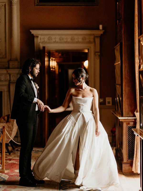 A bride and groom stand in the grand library at Harewood House in Yorkshire.
