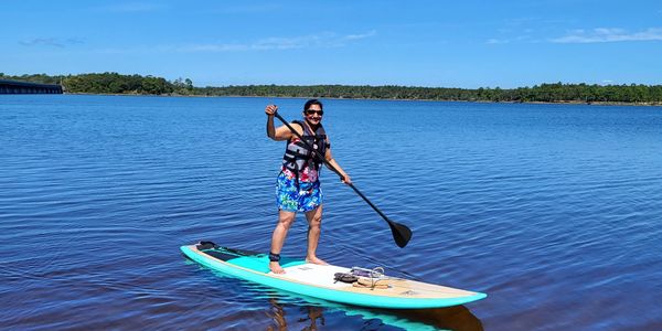 A person paddleboarding on a calm lake under a clear blue sky.