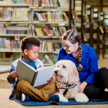 Kids at library reading a book with a Therapy Dog and its Handler