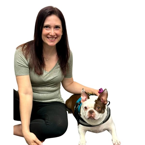 Picture of Chelsea sitting cross-legged next to Ducky who is laying on the floor