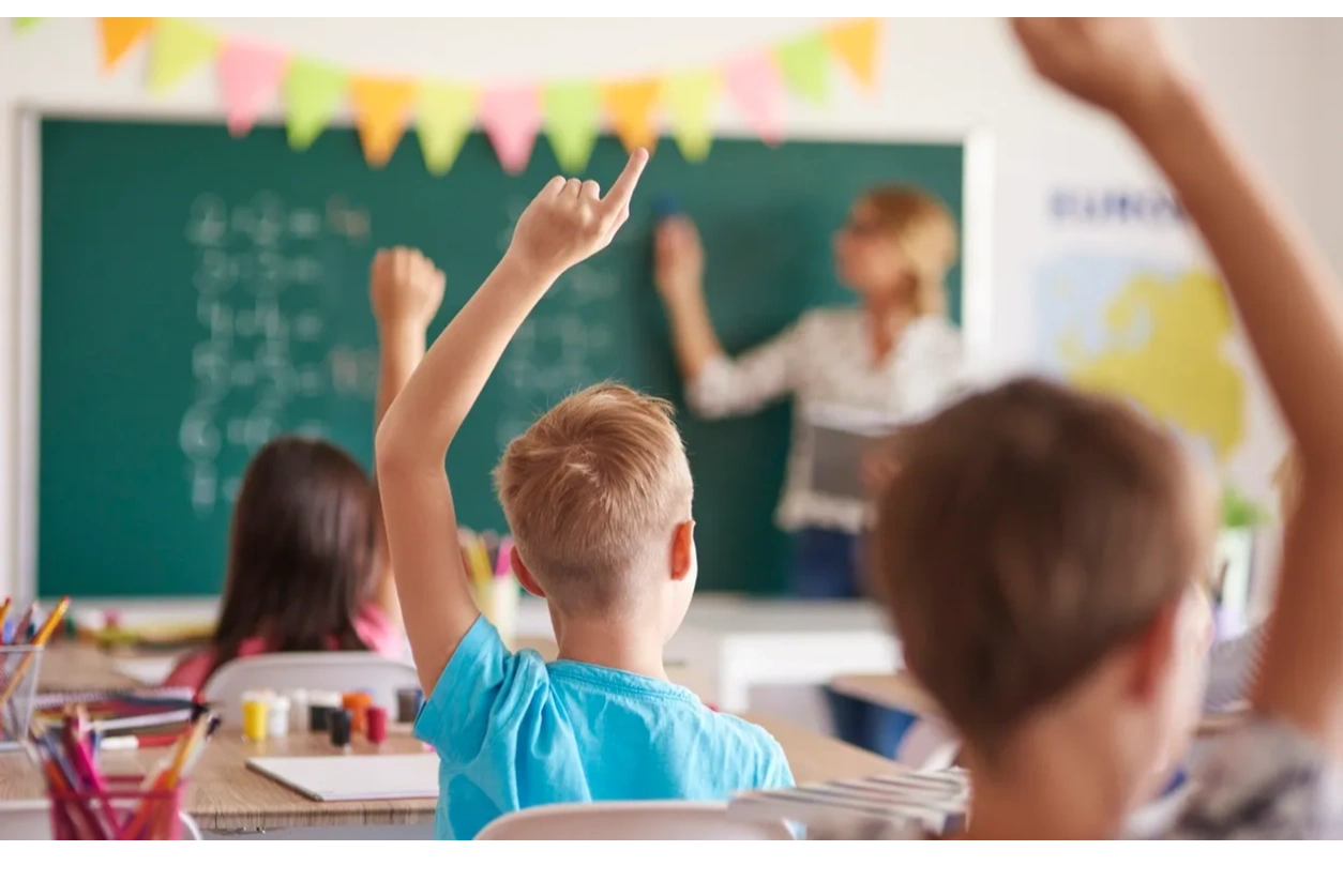 A child putting their hand up in a classroom