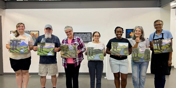 Group proudly holding landscape paintings.