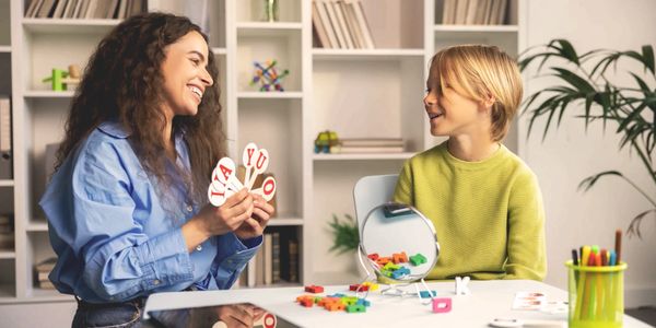 A woman and child playing an educational game with letter cards at a table.