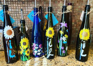 Painted bottles with various flowers and initials on them.