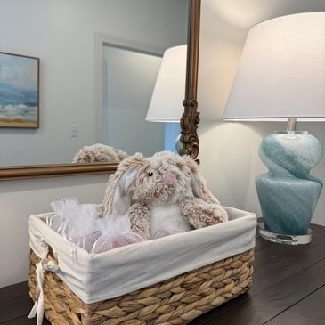 A plush bunny in a woven basket on a table.